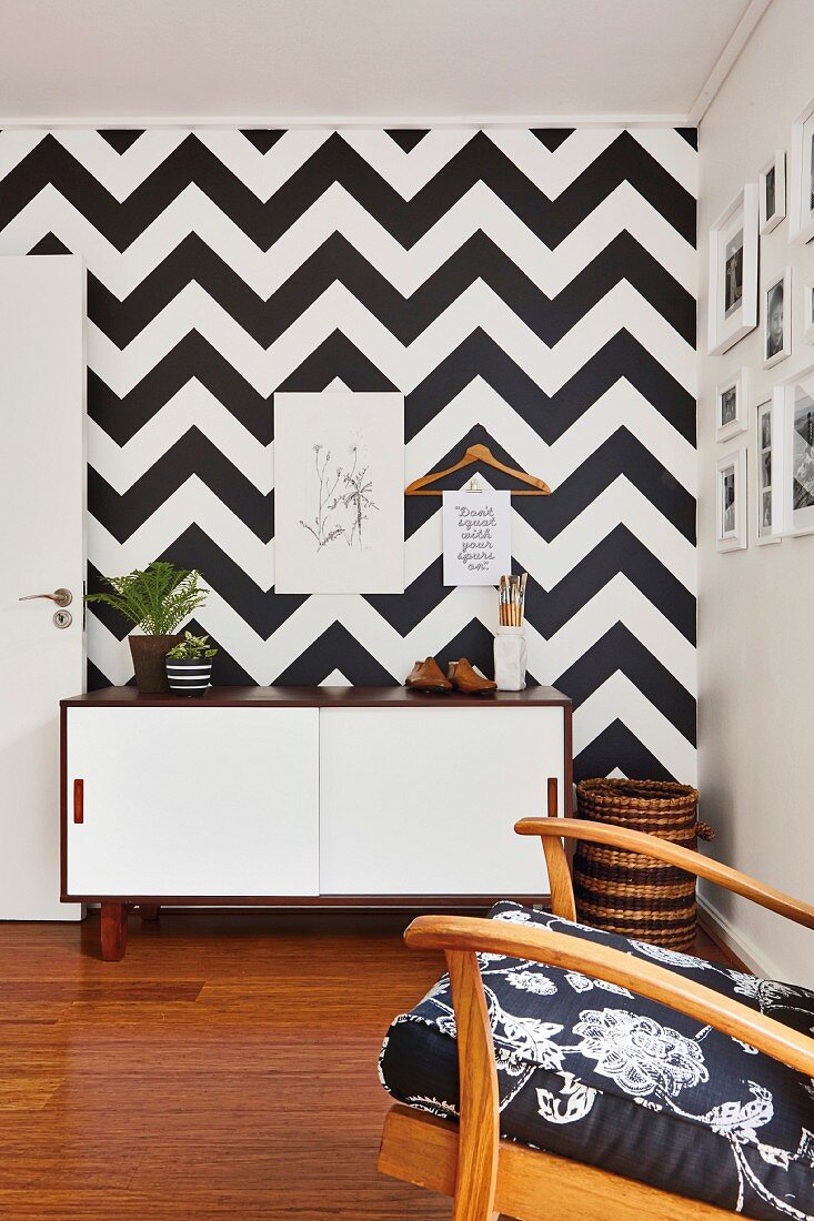 Sideboard mit weissen Schiebetüren vor Wand mit schwarz-weißem geometrischem Muster