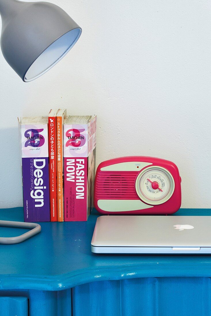Retro Radio neben Büchern und Schreibtischleuchte auf blauem Schreibtisch