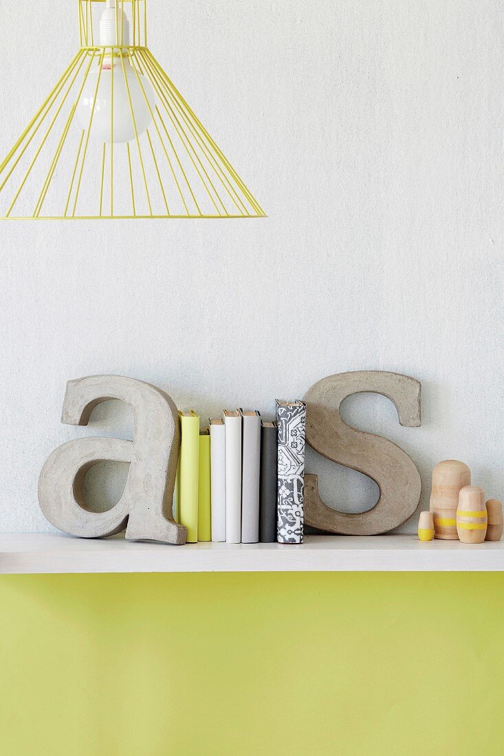 Decorative concrete letters used as bookends on shelf on wall