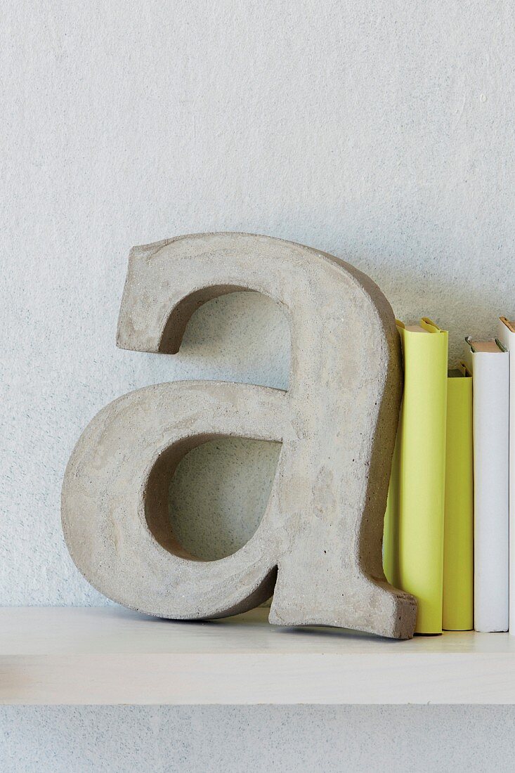 Decorative concrete letters used as bookends for books bound in white and yellow