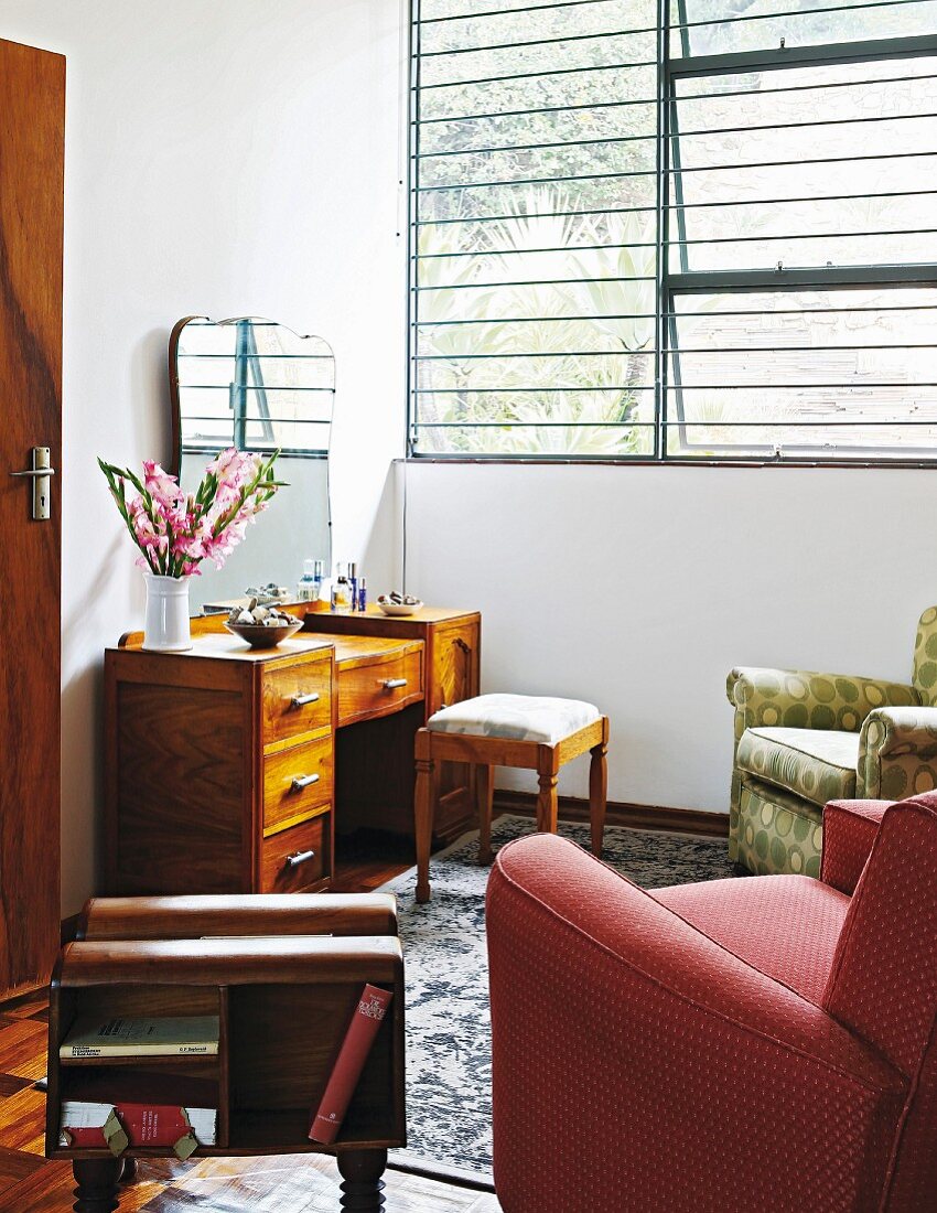Gemütliche Sessel und Schminktisch aus Holz in Zimmerecke, seitlich geöffnete Schwingfenster