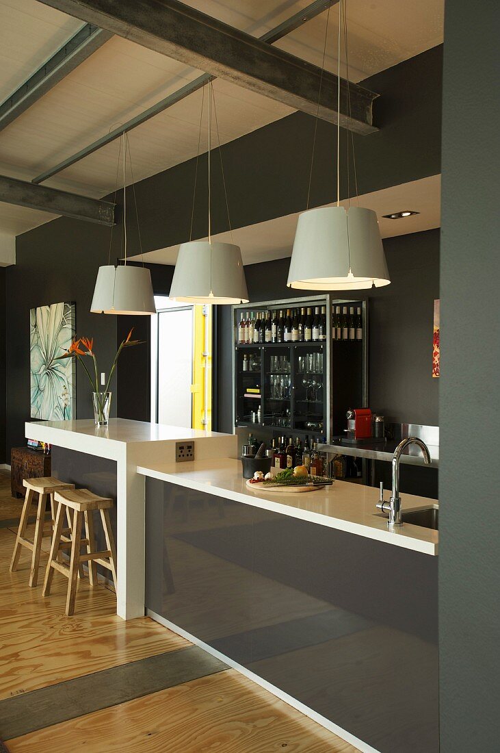 Pendant lamps above counter and breakfast bar with glossy fronts
