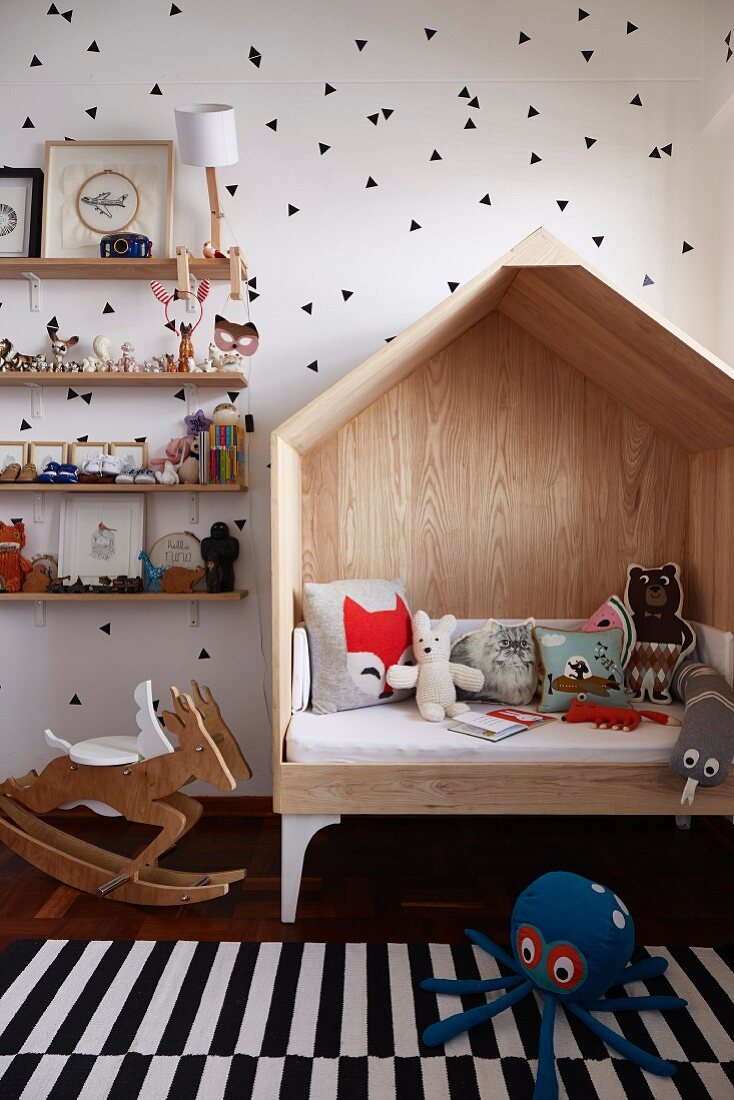Child's cubby sofa, rocking deer and ornaments on shelves against walls with pattern of stencilled black triangles