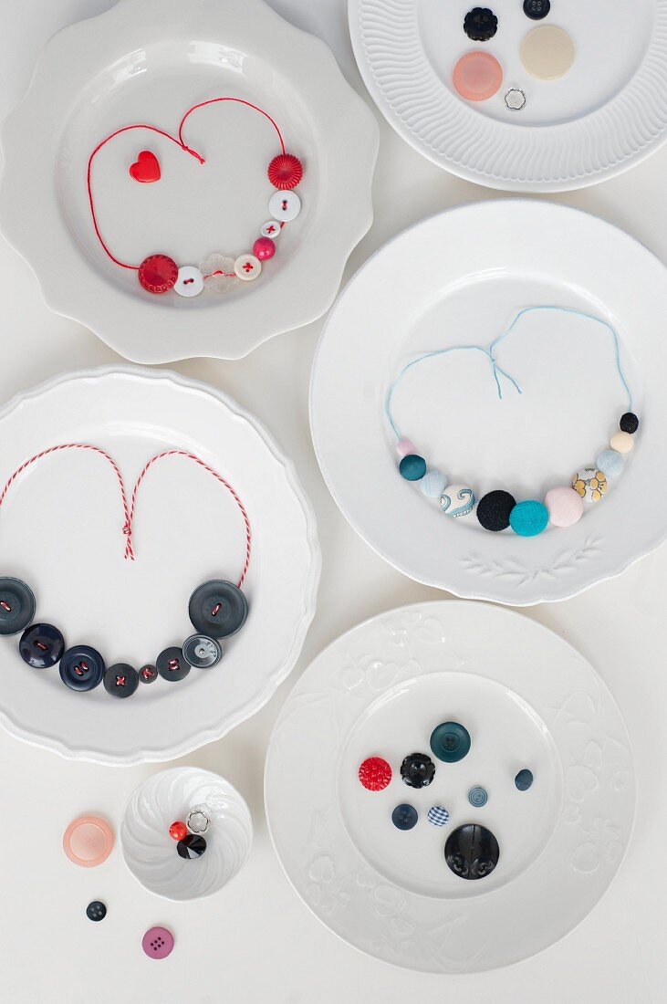 Necklaces made from colourful buttons and coloured cotton cords on plates