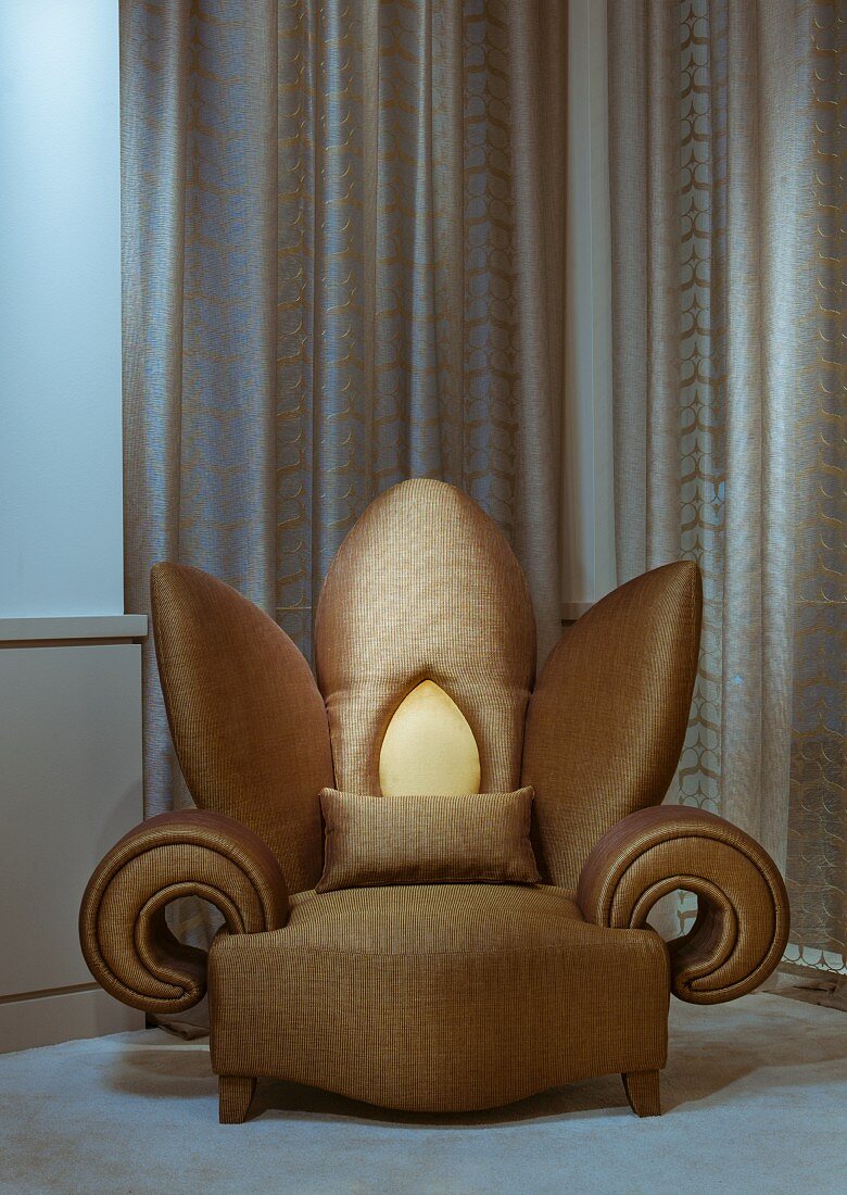 Extravaganter Sessel in Blumenform mit goldfarbenem Bezug vor bodenlangem Vorhang