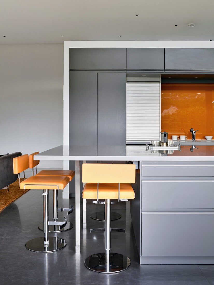 Orange bar stools at counter in grey modern kitchen