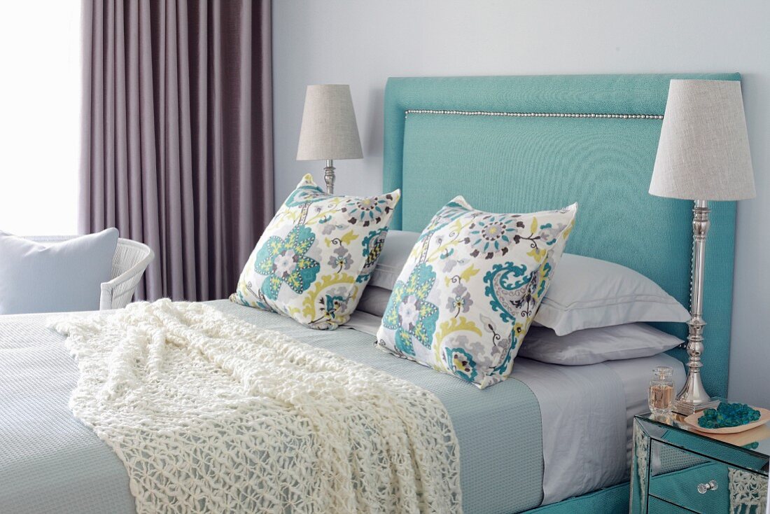 Elegant bedroom in shades of blue with turquoise upholstered headboard