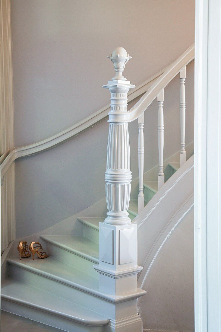 White-painted winding staircase with carved newel post