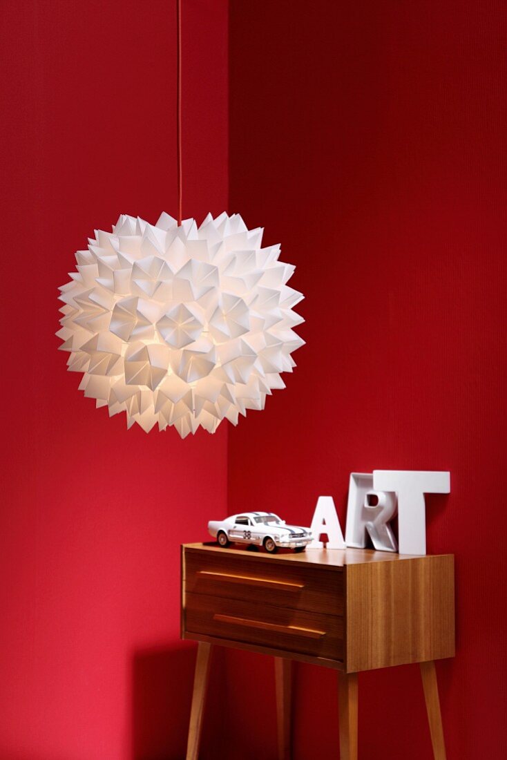 Origami lampshade in front of red walls