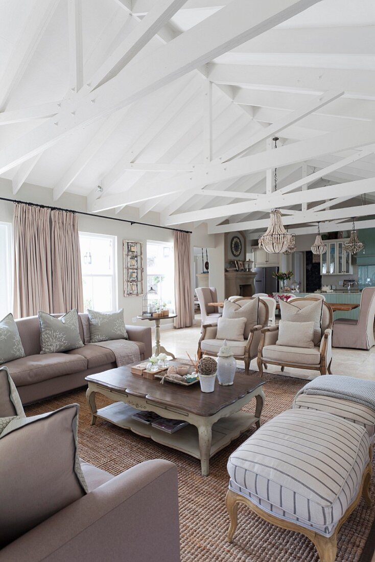 Upholstered furniture around coffee table below exposed roof structure in open-plan interior