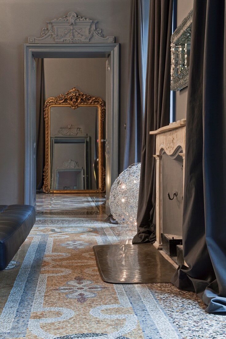 View through door with stucco elements onto antique floor mirror, terrazzo floor