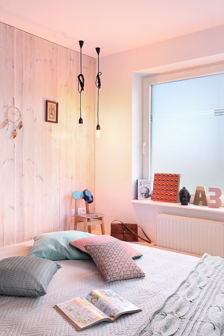 Wooden wall, window covered in frosted film and illuminated bulb-style pendant lamps in bedroom