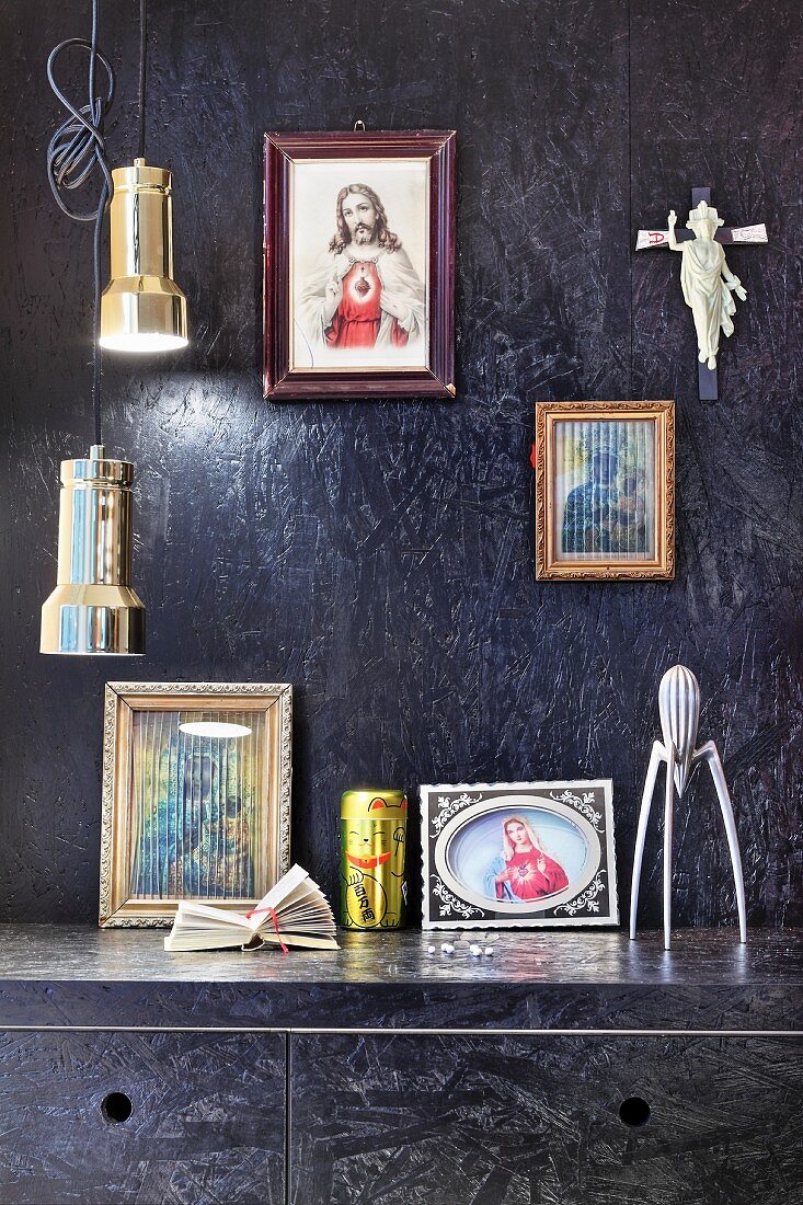 Schwarz gestrichene OSB-Platten an Wand und Küchenschränken, Ikonenbilder und Pendelleuchten