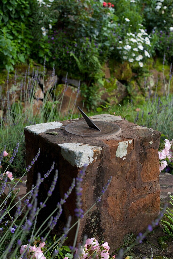 In Steinblock eingearbeitete Sonnenuhr aus Metall im Garten