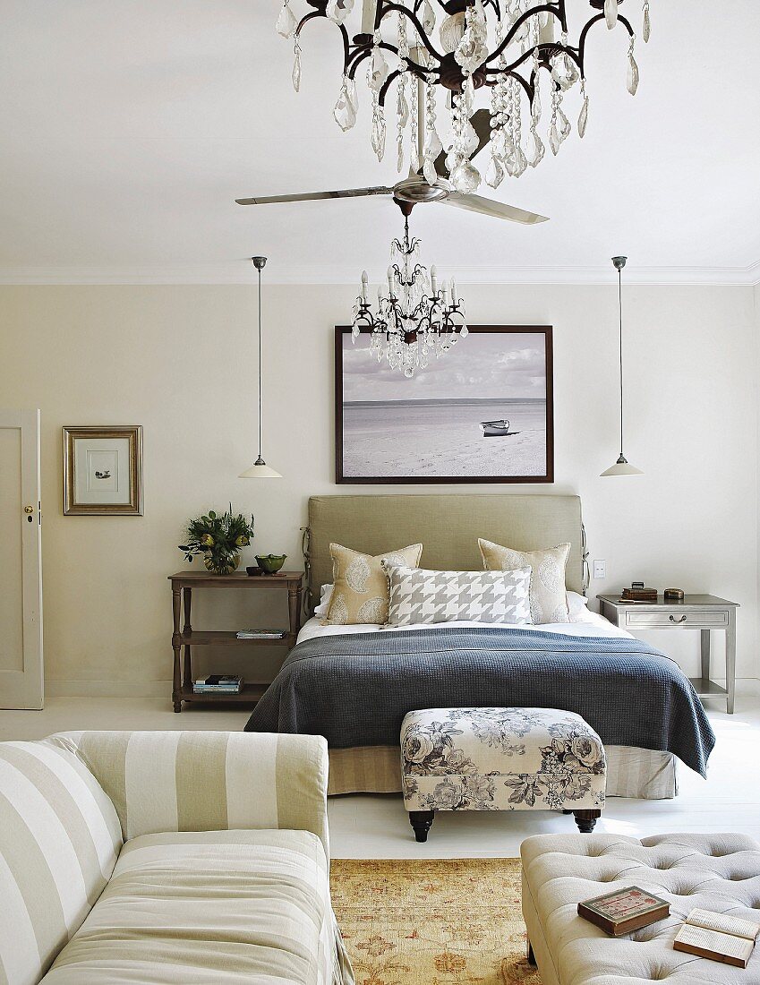 Mustermix im eleganten Schlafzimmer mit Sofa und Polsterhocker vor dem Bett