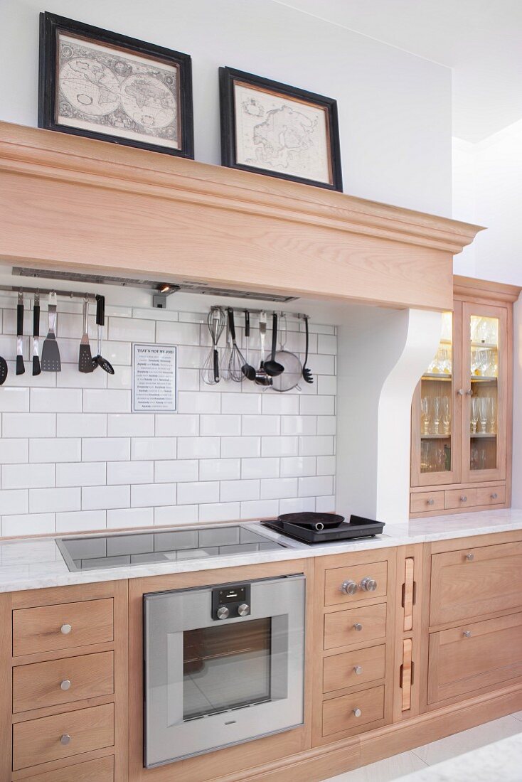 Pale wooden kitchen counter with wooden, profiled mantel hood above cooker