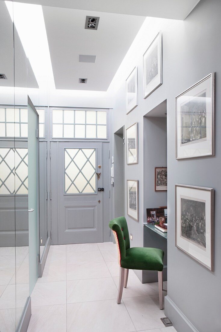 Narrow hallway with mirrored panels and workstation in niche with upholstered chair
