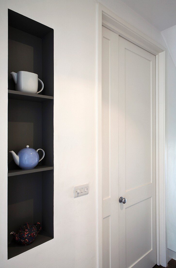 Teekannen in schwarz getönter Wandnische neben weisser Zimmertür
