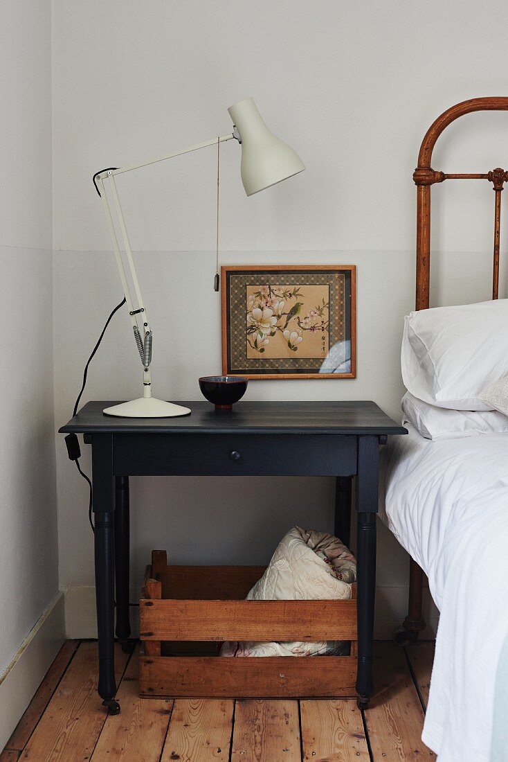 White retro table lamp on dark bedside table in corner of bedroom