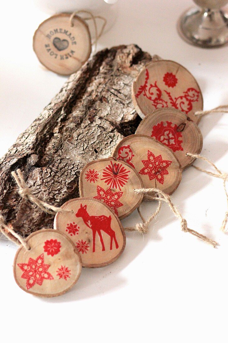 Girlande aus Holzscheiben mit roten weihnachtlichen Stempelmotiven bedruckt