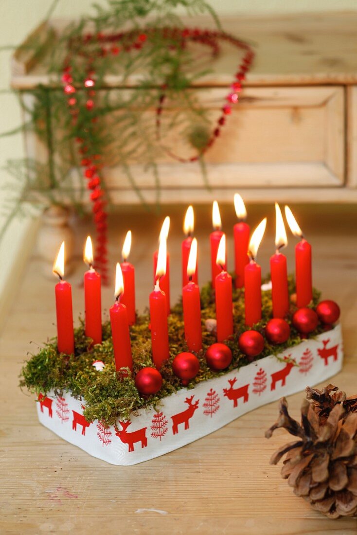Weihnachtliches Kerzengesteck mit roten Kerzen & Dekokugeln