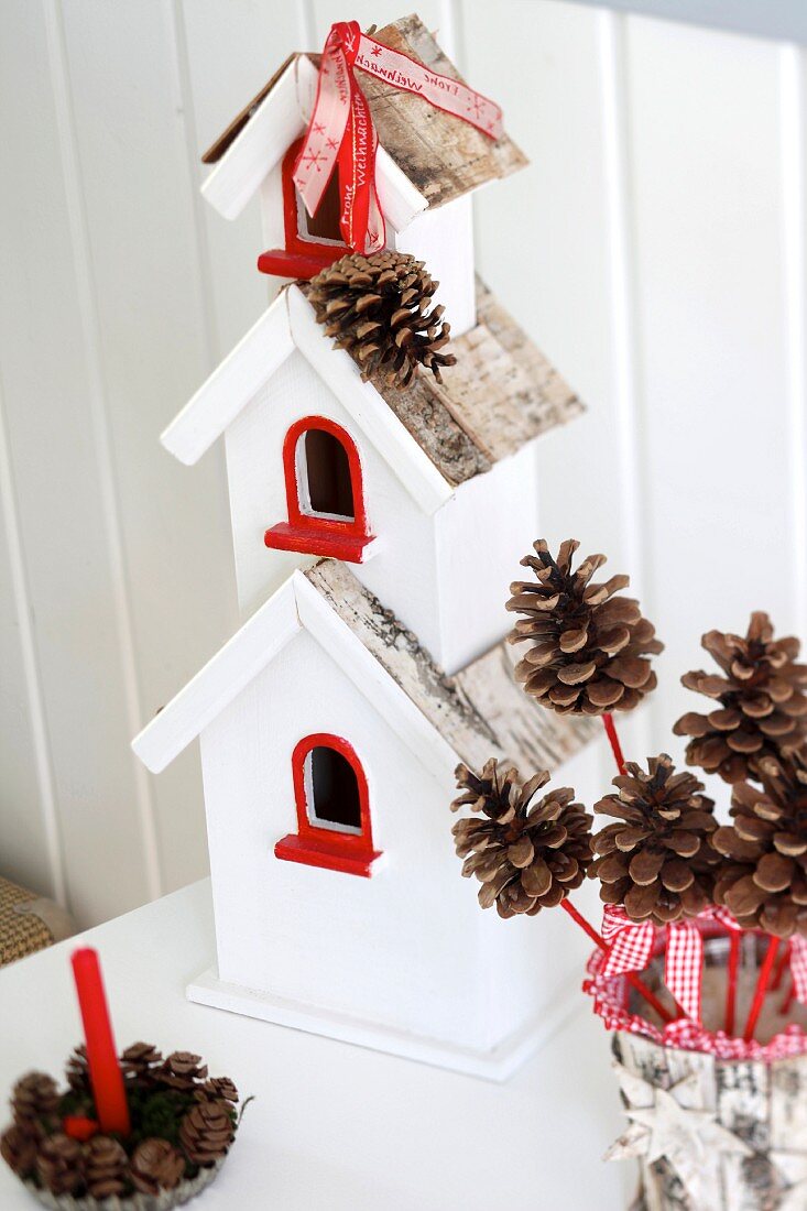 Red and white bird box decorated with ribbons & pine cones; Christmas arrangement