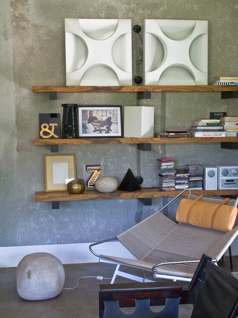 Seating area below wooden shelves on grey concrete wall