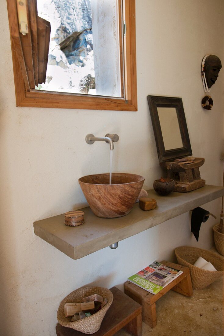 Waschbecken aus Holz und Holzschemeln unter dem verputzten Waschtisch
