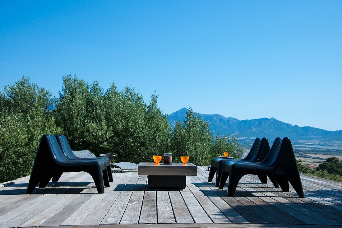 Moderne Sitzgruppe auf einer mit Holzplanken ausgelegte Terrasse umgeben von Olivenbäumen und traumhafter Aussicht
