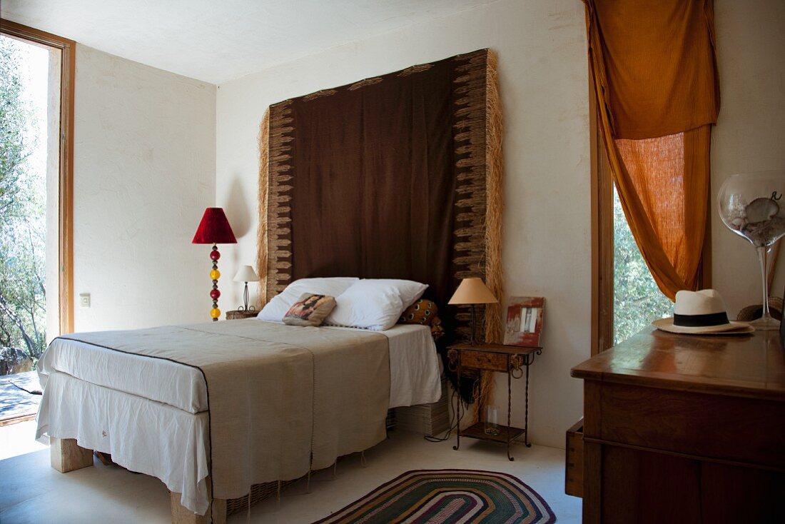 Schlafzimmer im Ethnostil, fransiger Wandbehang als Betthaupt
