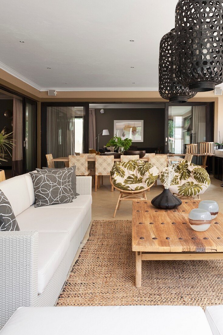 Lounge area with pale sofa, coffee table and lantern-style mesh pendant lamps in open-plan interior