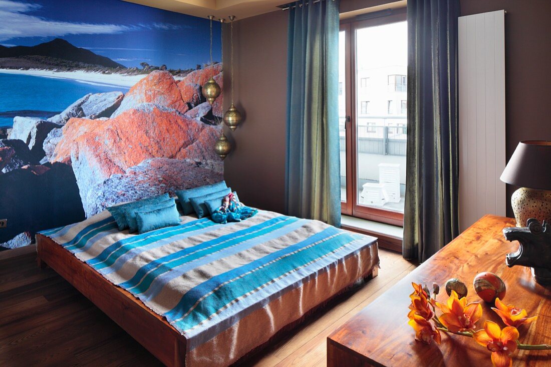 Doppelbett mit gestreifter Tagesdecke vor Poster, mit Meeresküste Motiv, an Wand