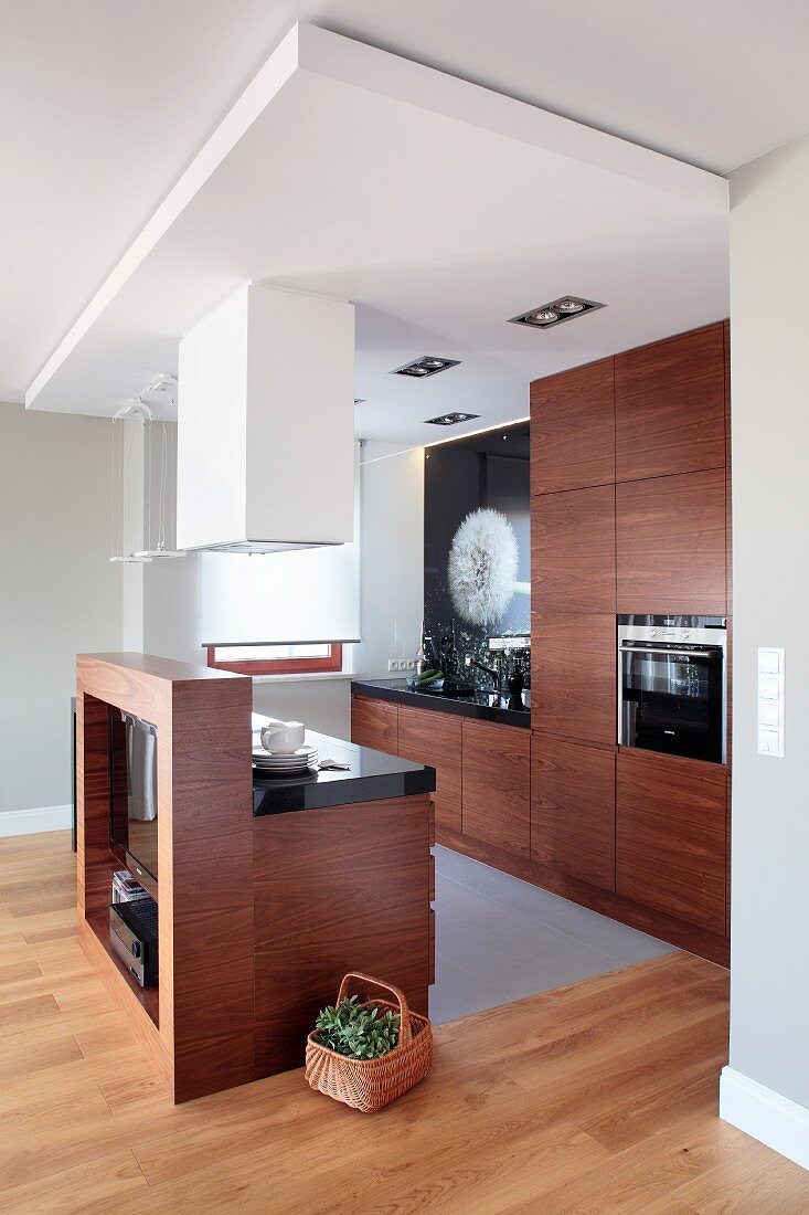 Open-plan designer kitchen with exotic wood fronts and black glossy worksurfaces