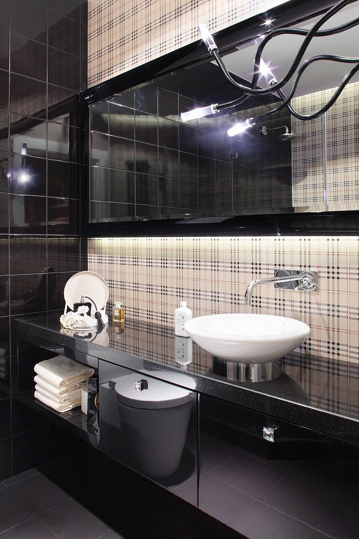 Washstand in designer bathroom with black glossy doors and back wall in subtle tartan