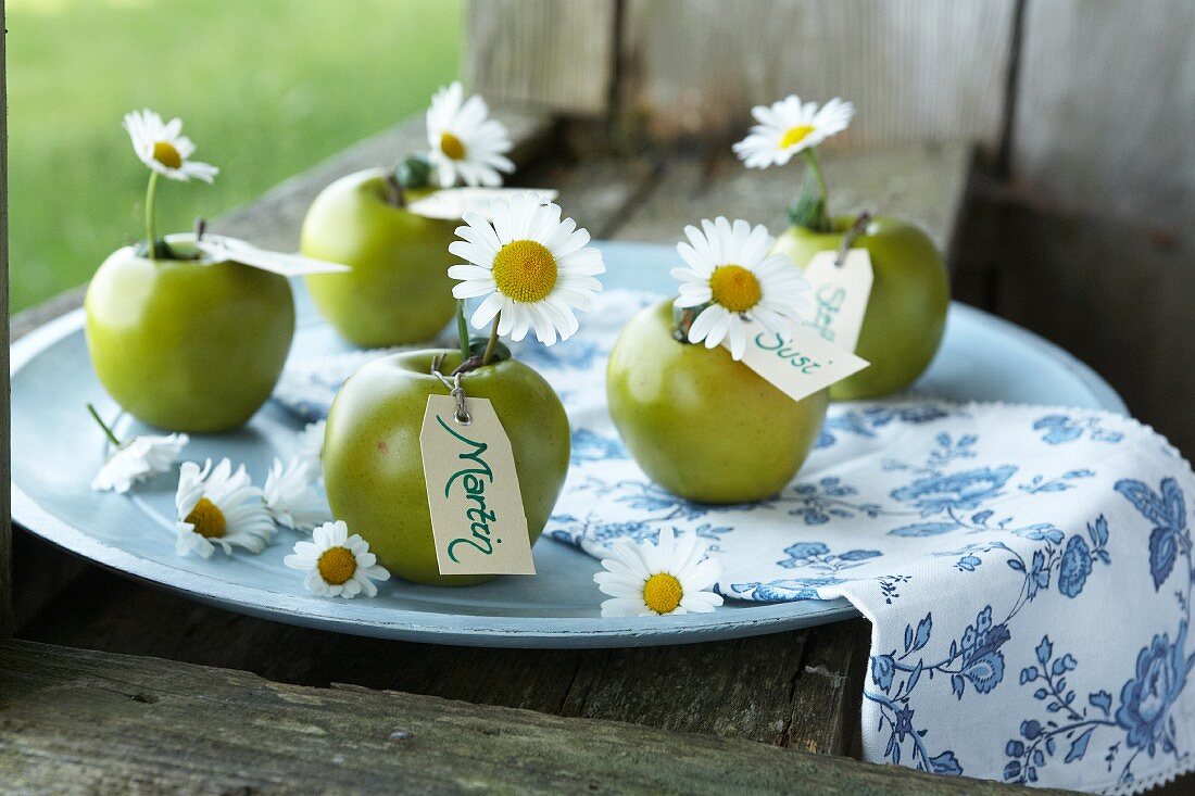 Grüne Äpfel mit Margeriten und Namenskärtchen als sommerliche Tischdeko