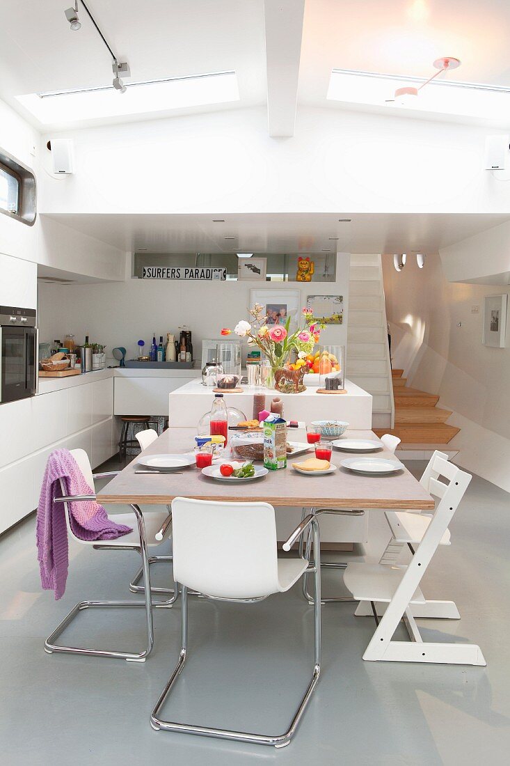 Cantilever chairs and Tripp Trapp child's chair around set dining table in open-plan houseboat interior