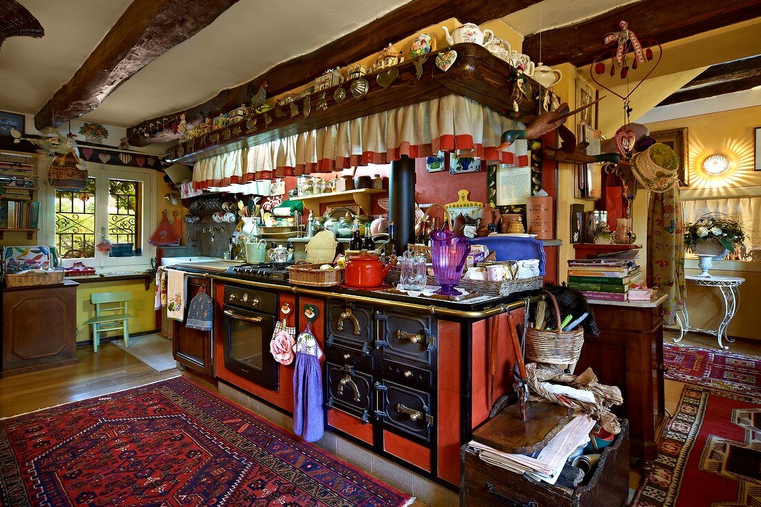 Vollgestellte Küchenzeile mit Antiköfen im offenen Wohnraum