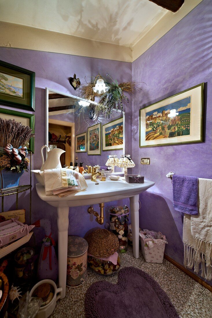 Elegant washstand against lilac walls in crammed bathroom