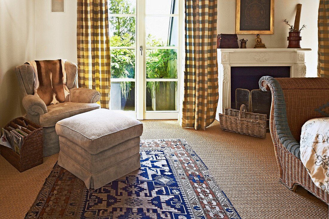 Polsterhocker und Sessel in Schlafzimmerecke neben Terrassentür mit bodenlangem Vorhang