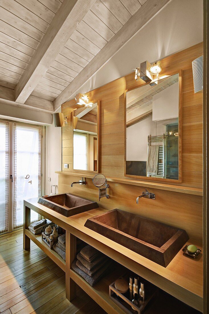 White-painted ceiling and custom washstand with twin sinks against wood-clad wall in bathroom