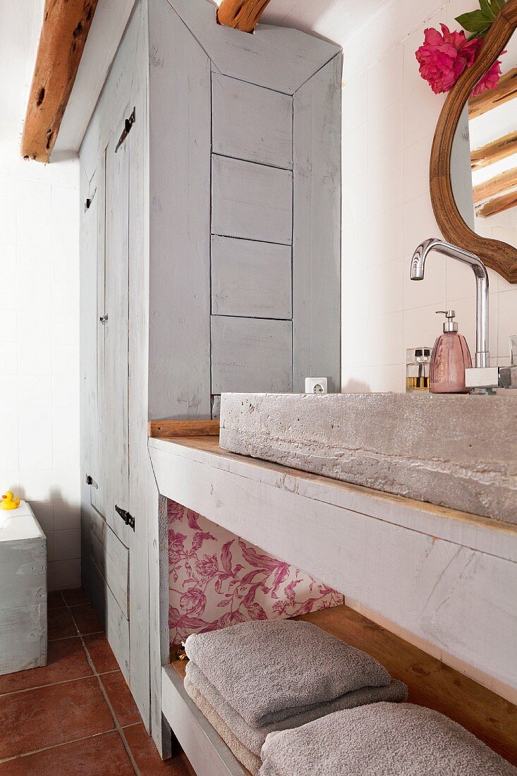 Rustikaler Waschtisch mit Beton Waschbecken unterhalb Ablage, im Hintergrund eingebauter Schrank mit hellgrau lasierter Holzfront