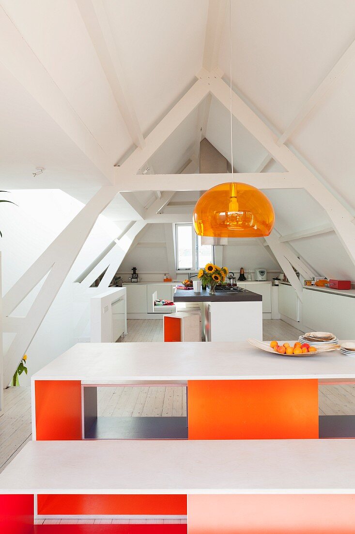 Designer Tisch und Bankgarnitur innenseitig farbig gestrichen unter Pendelleuchte in offener Küche