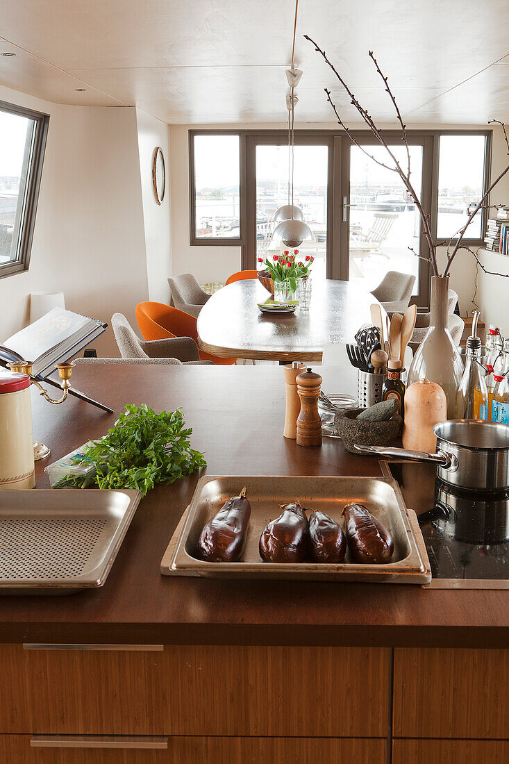 Kitchen utensils on counter with integrated hob in front of dining area of houseboat