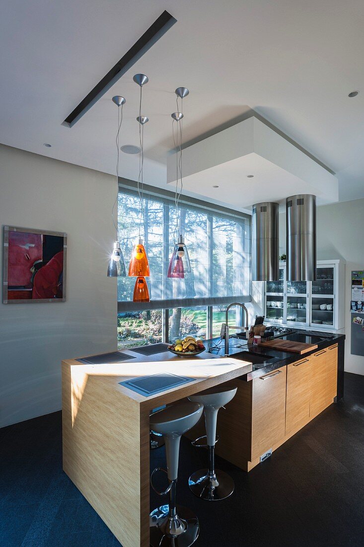 Designer-Küchentheke mit weißen Barhockern und Kücheninsel vor Fensterfront