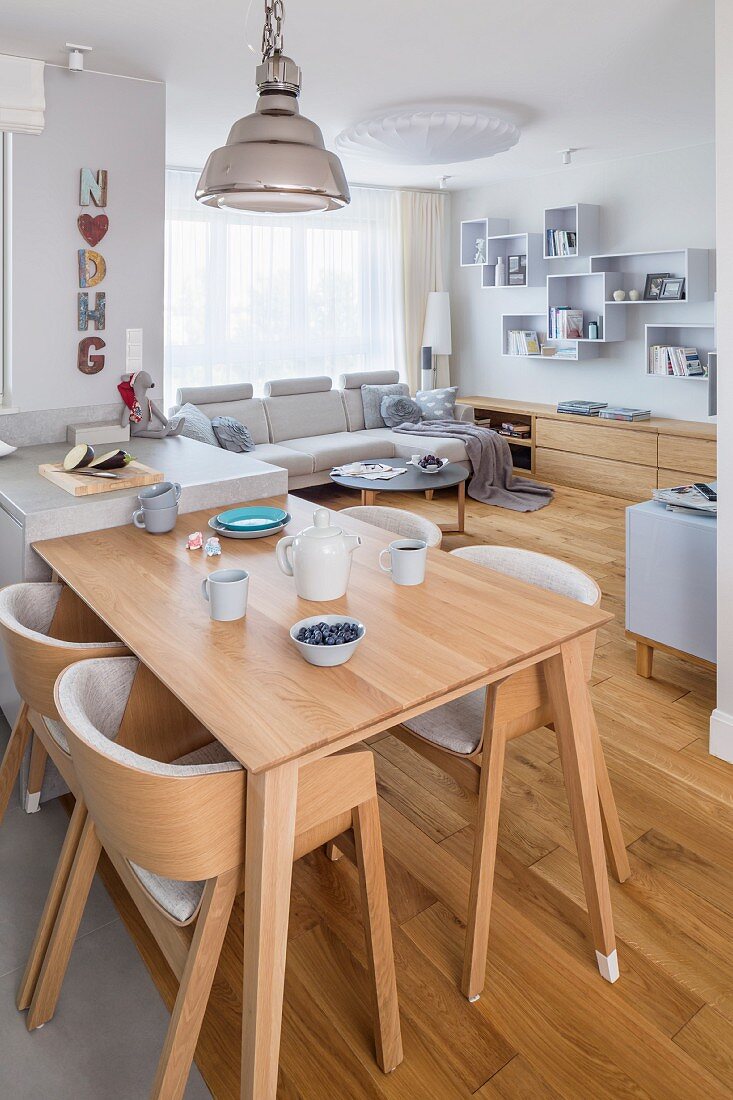 Offener Wohnraum mit schlichten Holzmöbeln und heller Polstergarnitur in kleinem Appartement