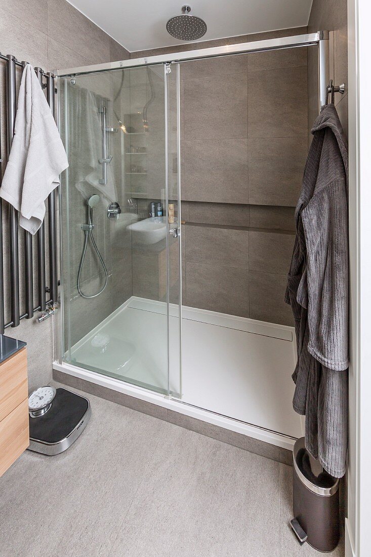 Spacious shower cubicle with sliding glass door and continuous shelf in niche