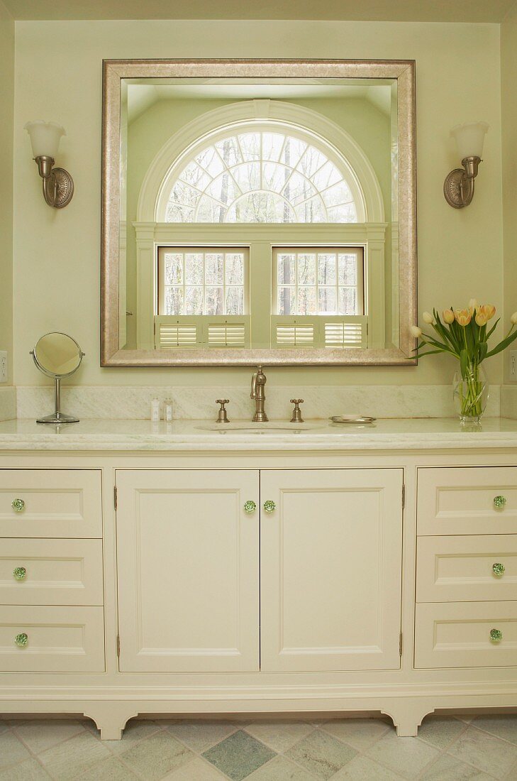 Washstand with marble counter below elegant mirror on wall