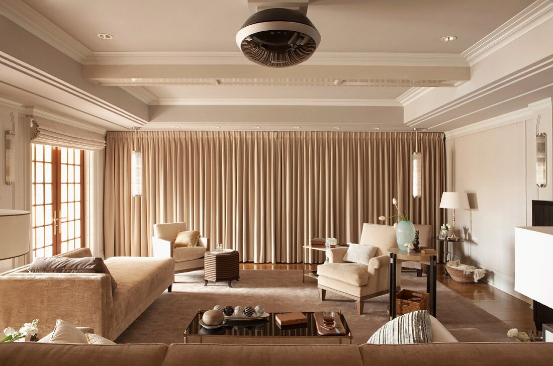 Spacious home cinema with floor-length curtains and comfortable upholstered furniture in elegant, country-house interior