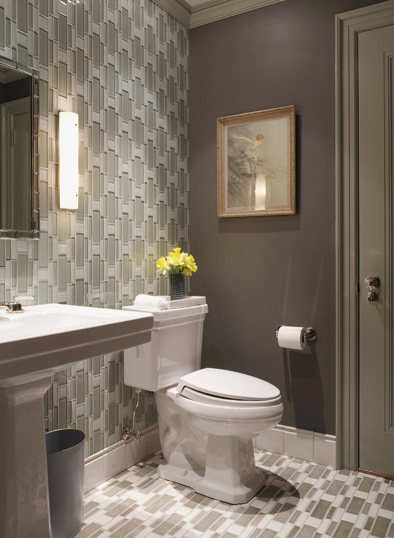 Badezimmer mit Toilette und gleichem geometrischem Tapeten- und Fliesenmuster