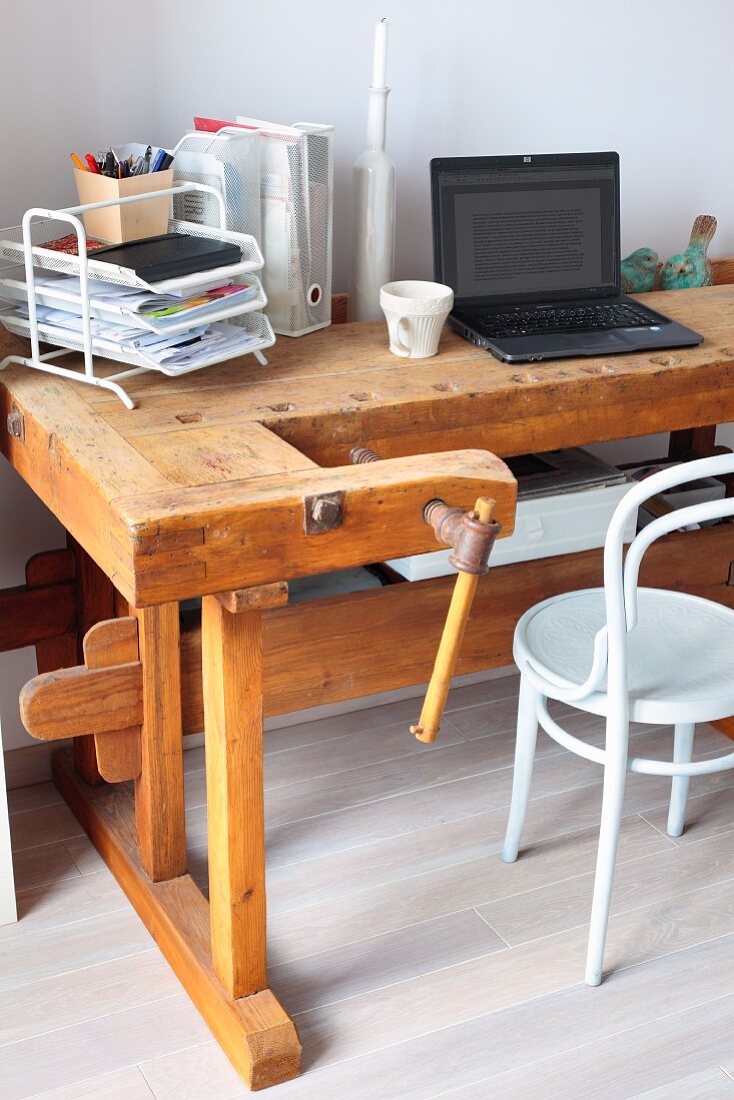 Old workbench used as vintage-style desk and white Thonet chair